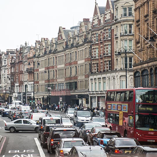 A busy street in London with several lanes of queuing cars and a red double decker bus