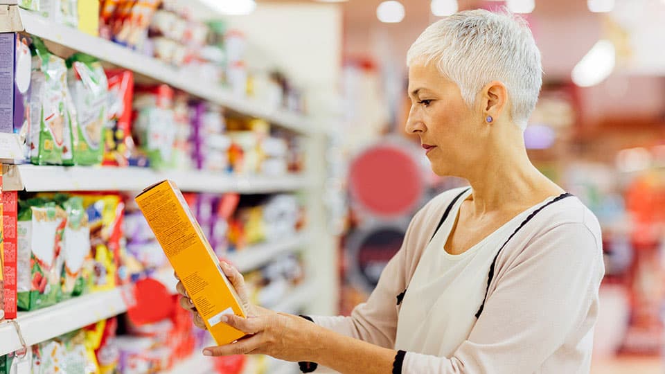 A woman in a supermarket looking at a packet of cereal