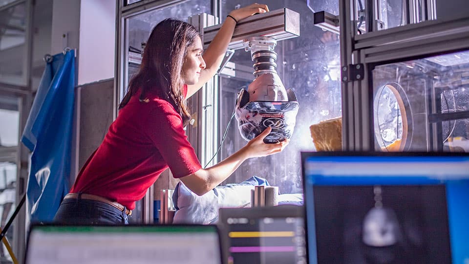 A female sports technology student carrying out an experiment on a cricket helmet