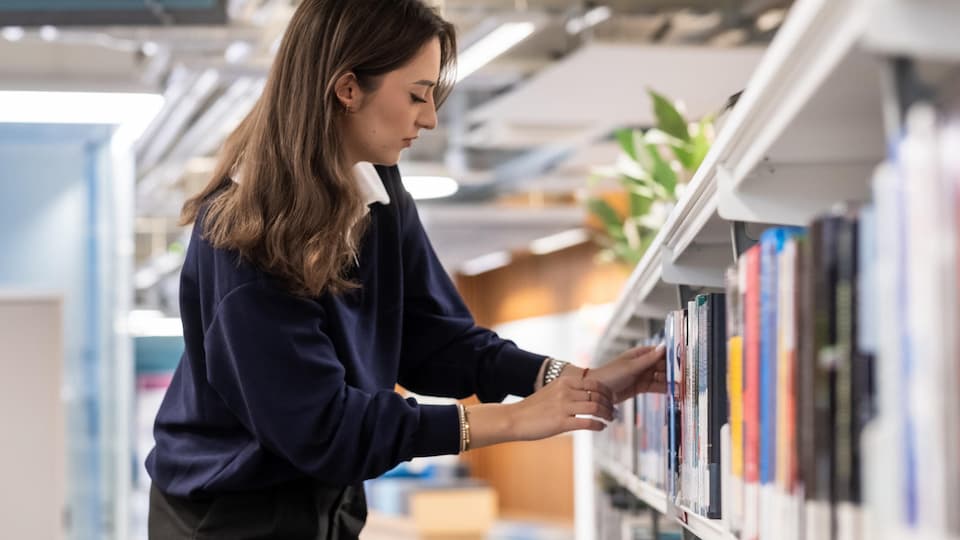 A person taking a book off a shelf in a library