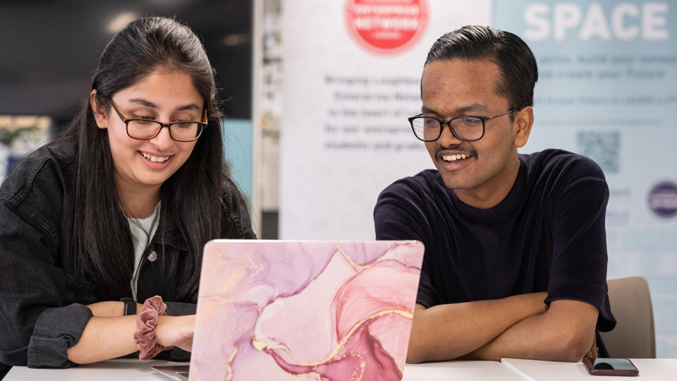 Two students looking at a laptop