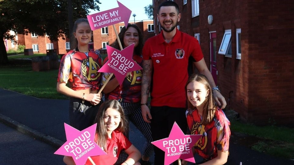 A group of students from Falkner Eggington Hall wearing red tops and holding signs