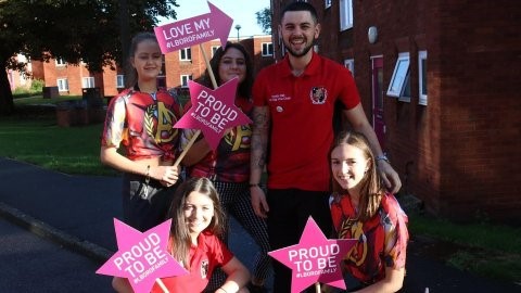 A group of students from Falkner Eggington Hall wearing red tops and holding signs