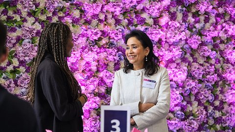 Two people chatting. There is a purple flowery background.