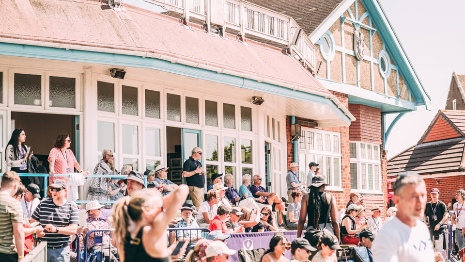 A busy scene of people wearing caps and summer clothes in front of the Pavilion
