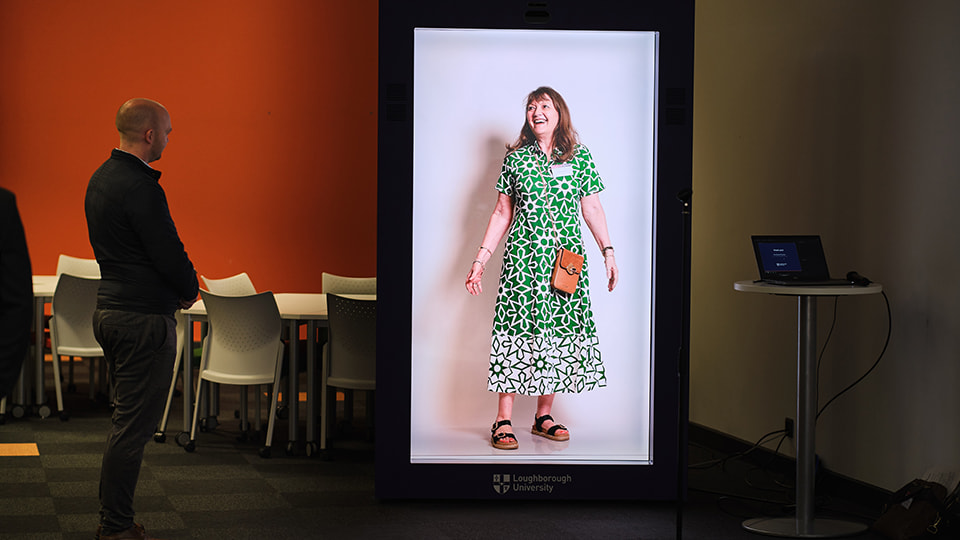 An image of a person in a hologram machine. There’s another person looking towards the machine.