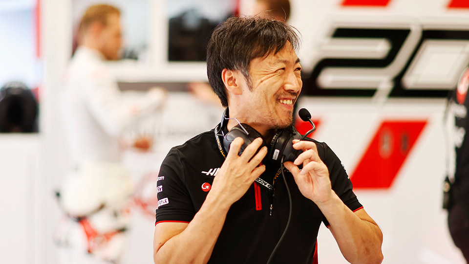 Ayao smiling. He is holding a headset around his neck.