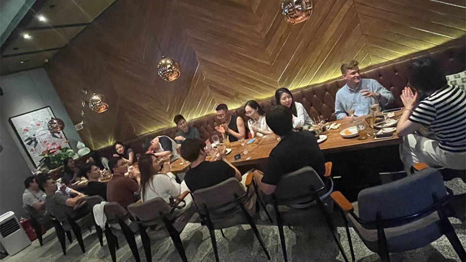 A group of alumni sat on a table having socialising