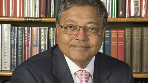 Mihir Bose in front of shelves full of books.