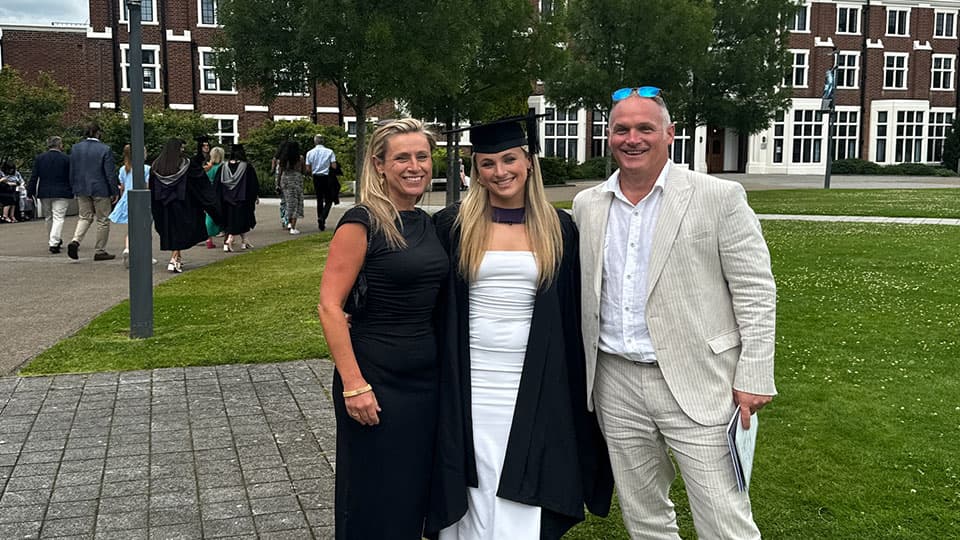 Beth Higgins and her parents, Daniel Higgins and Helena Higgins in front of Hazlerigg Building standing together and smiling.