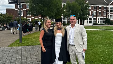 Beth Higgins and her parents, Daniel Higgins and Helena Higgins in front of Hazlerigg Building standing together and smiling.
