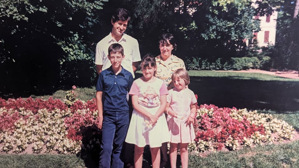 Famille-Fouilland standing in front of a bed of flowers in 1985.