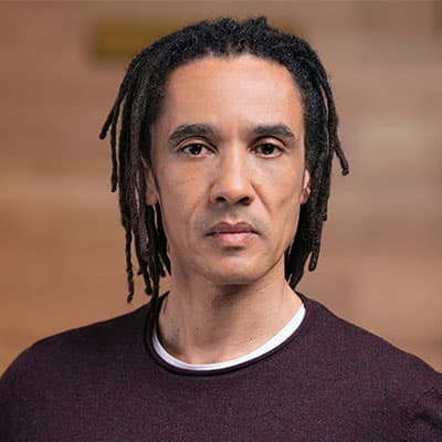 A headshot of Phil Tulba, there is a pain background which is blurred.