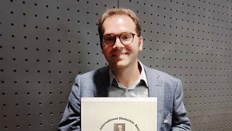 Stavros holding The Debye Prize 2024 and smiling against a plain background.