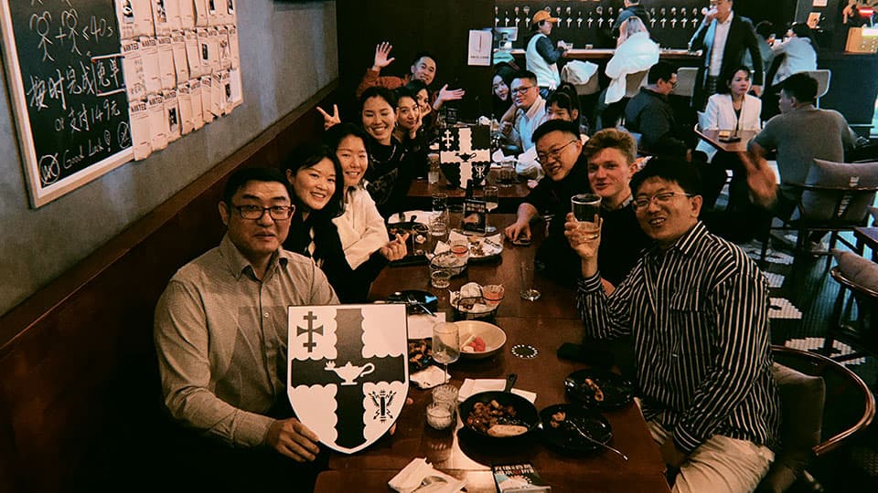 A group of alumni at Loughborough University's alumni gathering in Beijing on 7th November 2024. They are sitting and smiling with drinks at a table at a local beer bar.