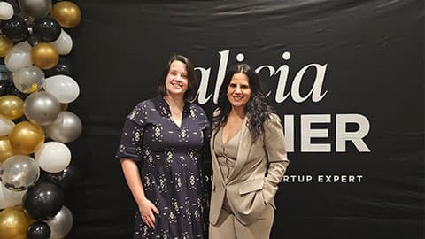 Alicia Soulier, CEO of SalonScale standing with Founder of CEO Stories Media with a black background and some gold, white, black and silver balloons to the left.
