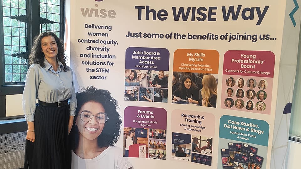 Lucy standing next to a large banner detailing 'The WISE Way' wise women's network