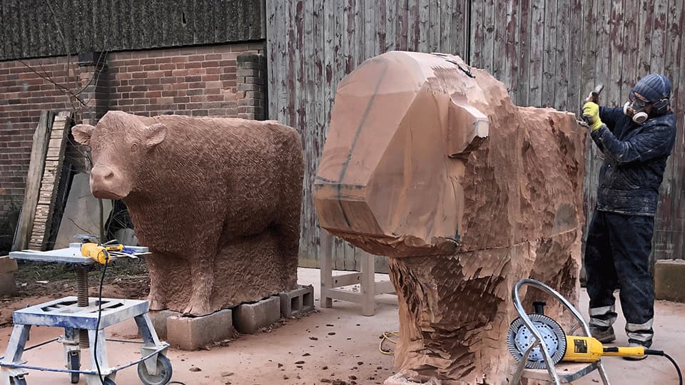 Graeme carving a Lincoln Red bull and heifer from Cove Red sandstone at his workshop in Leicestershire.