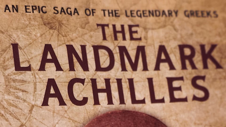 A screenshot of 'The Landmark Achilles' book by James Briana. The title reads The Landmark Achilles, an epic saga of the legendary greeks, in red and is against a background which looks worn like an ancient manuscript.