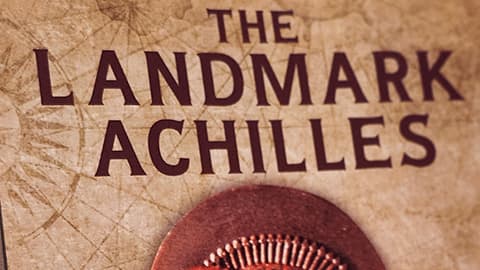 A screenshot of 'The Landmark Achilles' book by James Briana. The title reads The Landmark Achilles, an epic saga of the legendary greeks, in red and is against a background which looks worn like an ancient manuscript.