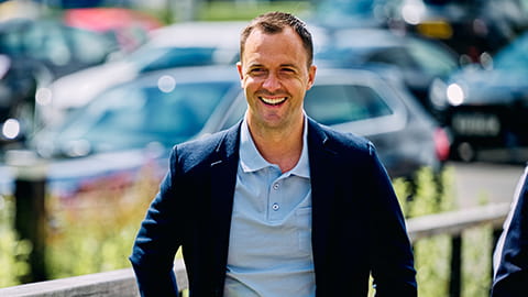Chris Davies smiling. He wears a polo shirt and suit jacket.