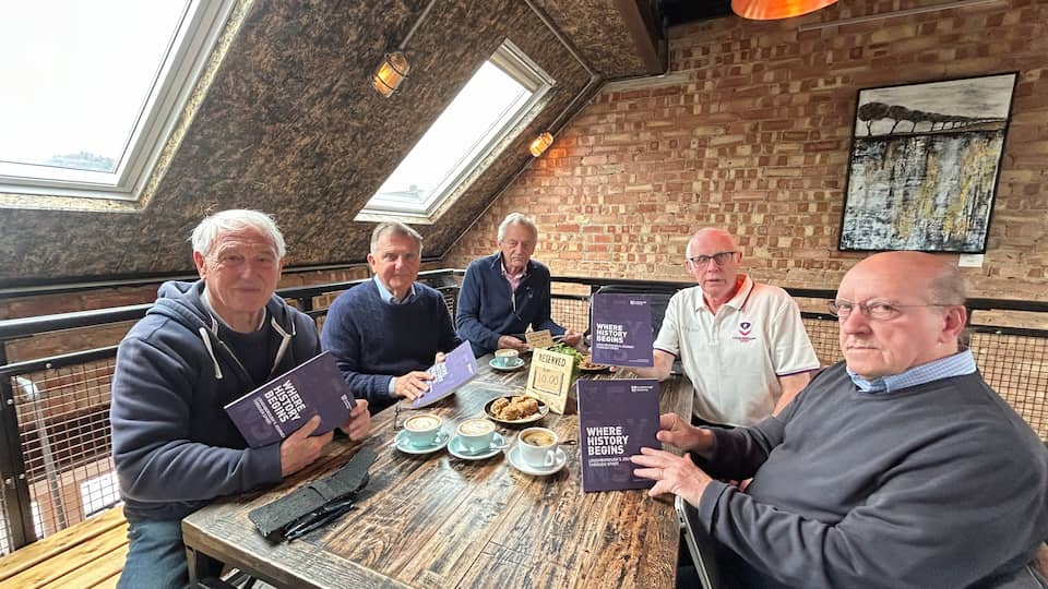 Five people at a table holding a book each