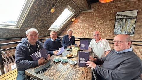 Five people at a table holding a book each