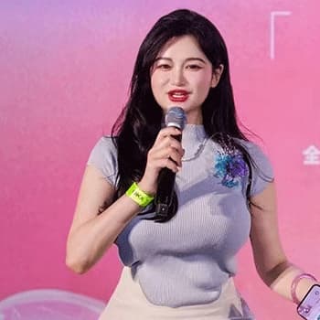 Fangyi Duan wearing a lilac top with a microphone in her hand. The background is pink.