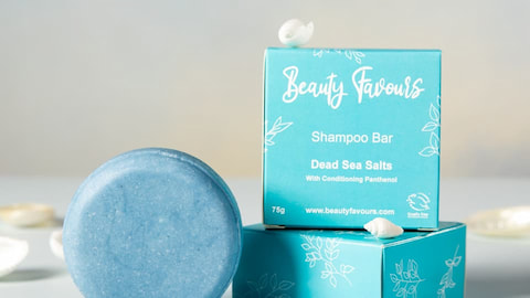 A round piece of blue shampoo bar and a square, blue package for the shampoo bar