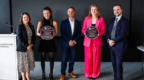 Sri and Katie holding their Purple Plaque Awards smiling at the camera with colleagues from the University