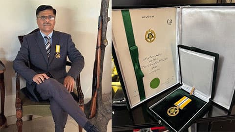 Kazim is wearing a navy suit and sitting down wearing the medal on one half of the image and on the right there is a close up of the medal.