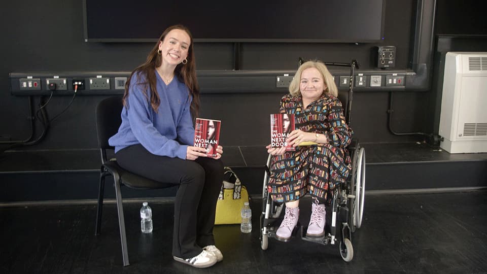 Penny at Loughborough Literary Festival 2025 holding her fourth book The Woman Next Door and she is smiling.