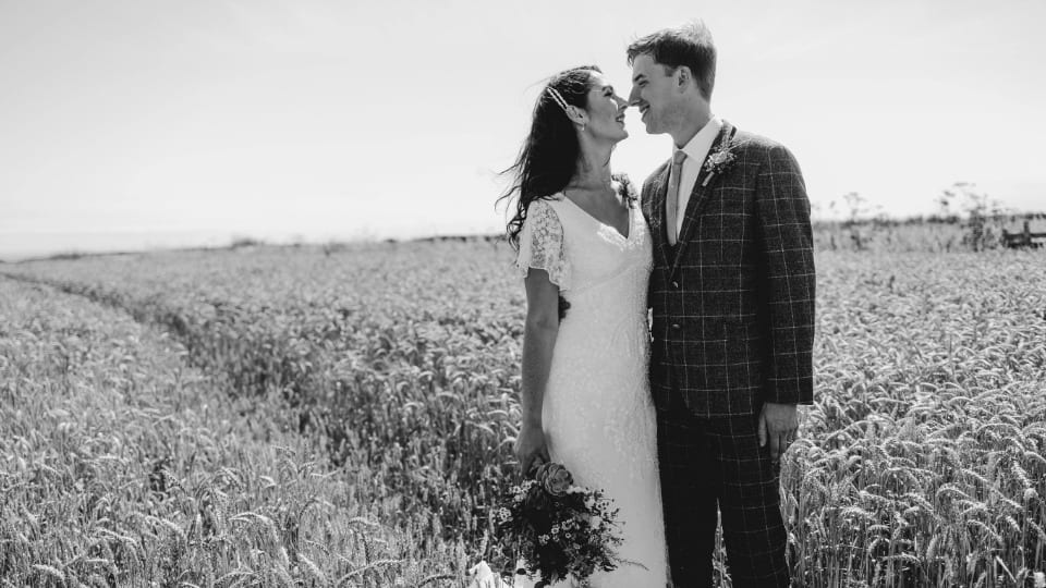 A couple wearing wedding clothes standing in a field