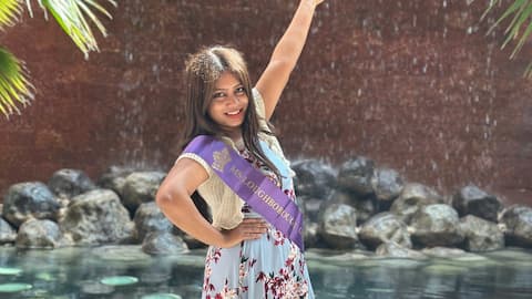 Ash wearing a sash. She is pointing up, in a pose.