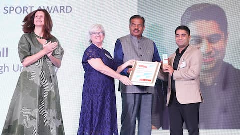 Aman Dhall accepting his certificate on stage with three other people