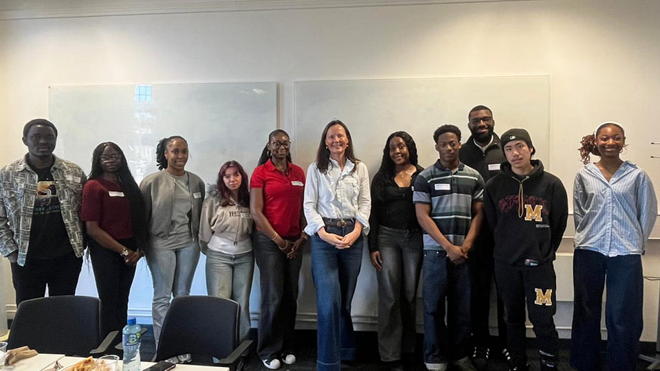Sarah, centre, with students standing each side in a lecture room