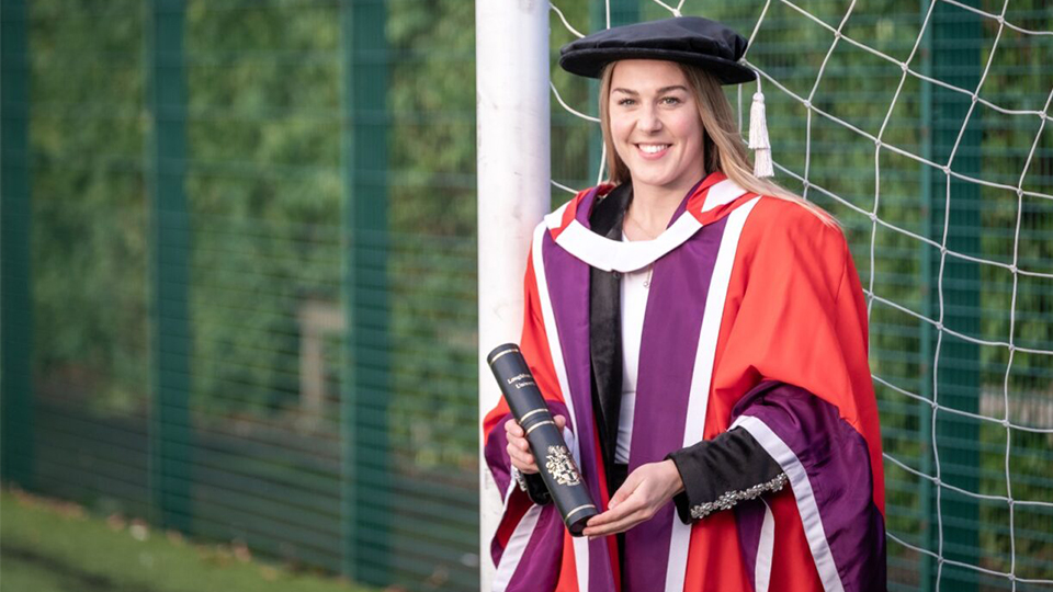 Mary Earps smiling and holding her degree wearing the graduation cap and gown