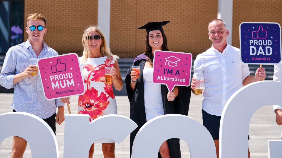 Family of four celebrating the graduation of their daughter in the sunshine on Shirley Pearce Square.