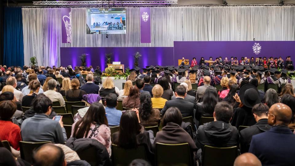 View of the Graduation ceremony stage, with graduands in their gowns and hats.