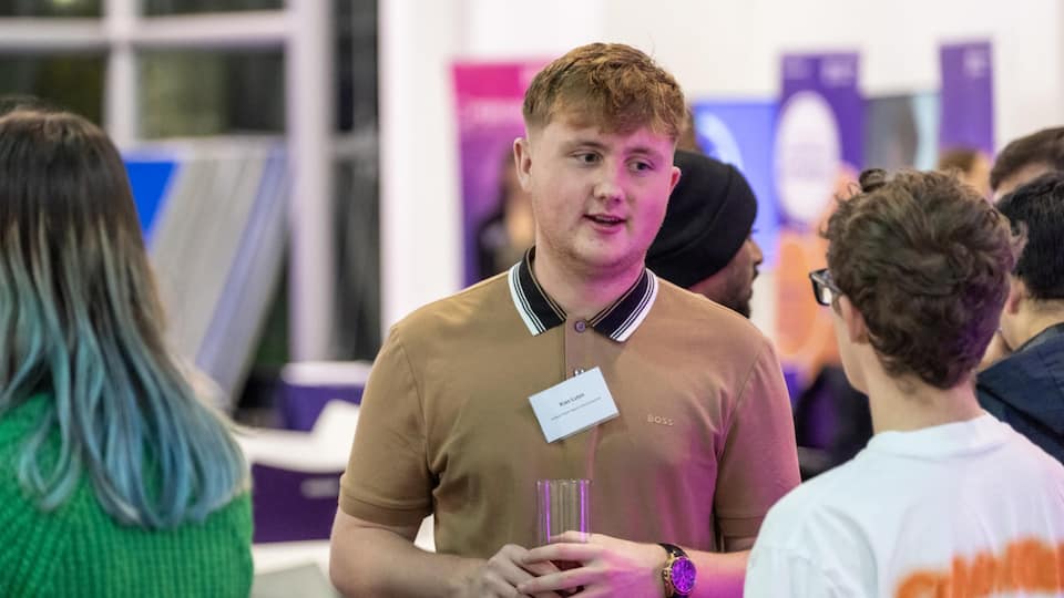 A student, centre, talking to someone