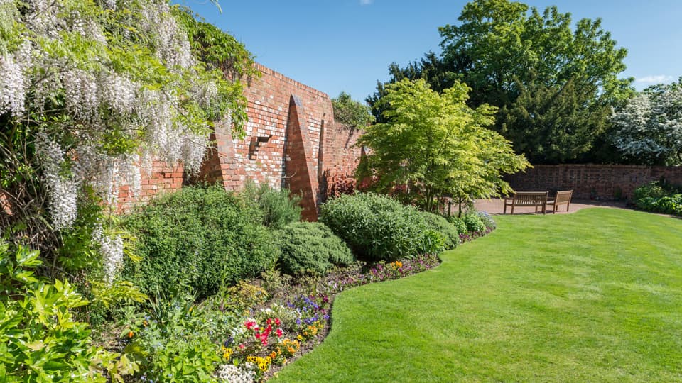 The Garden of Remembrance with a wall, plants, grass, and benches