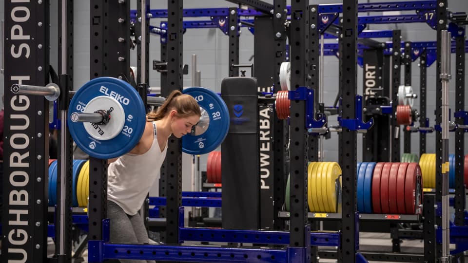A person lifting weights on equipment in Powerbase Gym. There is more gym equipment in the background.