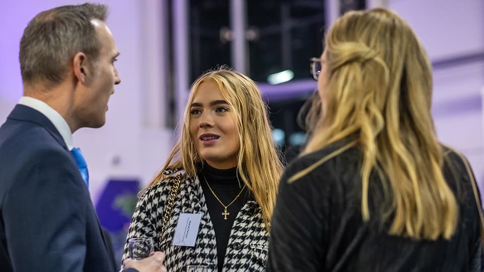 Three people, with one facing forwards towards the other two people. 