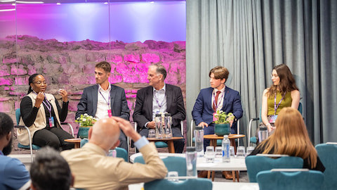 Five people seated on a stage facing an audience