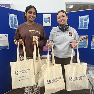 Two people holding Loughborough University tote bags
