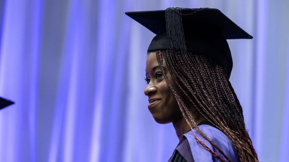 A graduate smiling wearing a cap and gown
