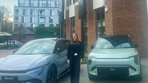 Emma standing between two cars