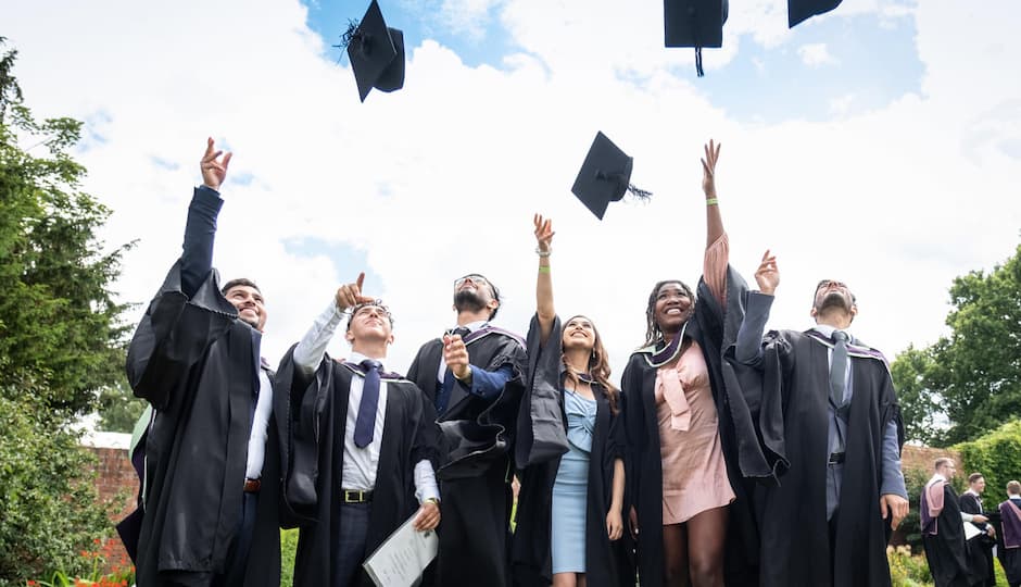 A group of people wearing graduation gowns and throwing their caps in the air