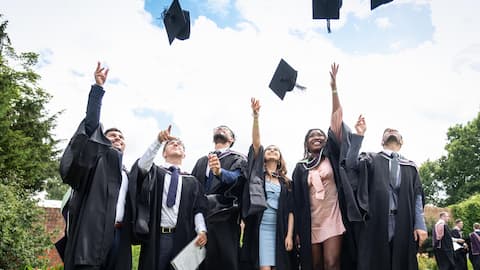 A group of people wearing graduation gowns and throwing their caps in the air