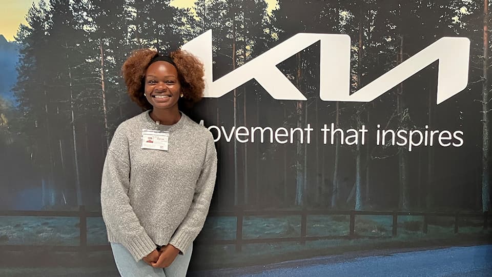 Janetbest standing in front of a Kia sign